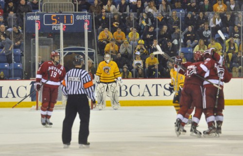 <h3>Harvard 6, Quinnipiac 3</h3>Quinnipiac goalie Eric Hartzell looks on as Harvard players celebrate Danny Biega's game-tying goal in the second period in Friday's game.