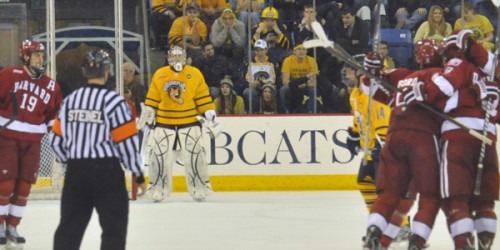 Quinnipiac goalie Eric Hartzell looks on as Harvard players celebrate after Danny Biega scores the game-tying goal in the second period.