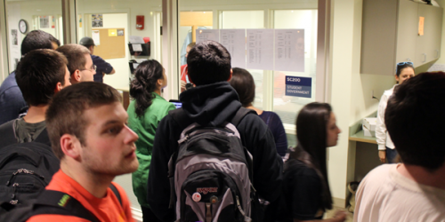 Candidates and students check the election results posted on the window of the SGA suite in the Carl Hansen Student Center Wednesday night.