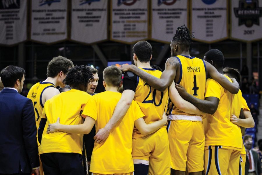 The mens team gathers in the huddle during a timeout.