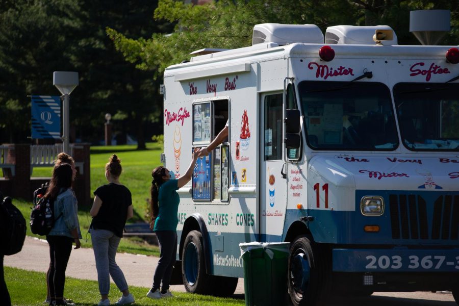 Student is purchasing a cup of chocolate ice cream from Mister Softee truck on campus.