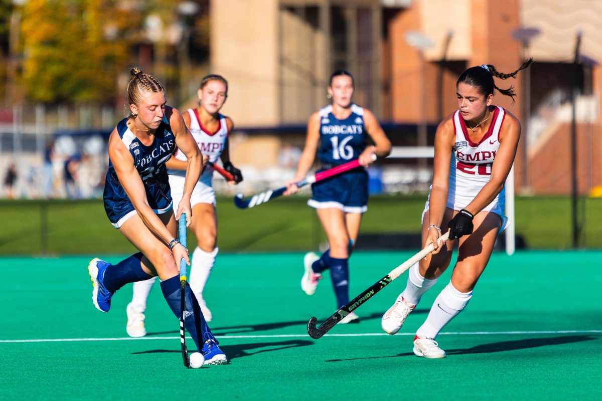 Sophomore forward Cameron Brower, left, dribbles the ball past freshman forward Mathéa Lassalle of the Owls, far right, during the Bobcats' 3-2 overtime loss against Temple University on Friday, Oct. 27, 2023 at the Quinnipiac Field Hockey Stadium.