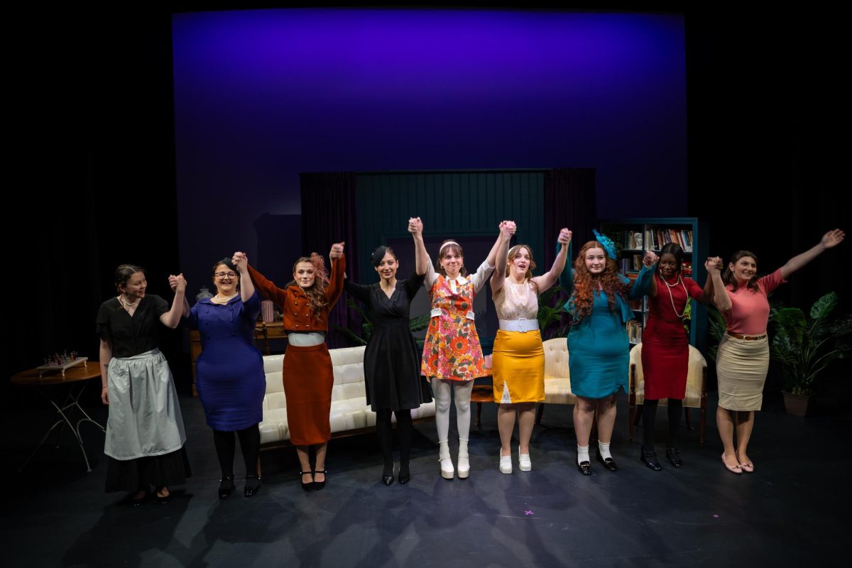 The cast of “Murder By Membership Only” celebrates in front of the set at the end of their last rehearsal on March 21.