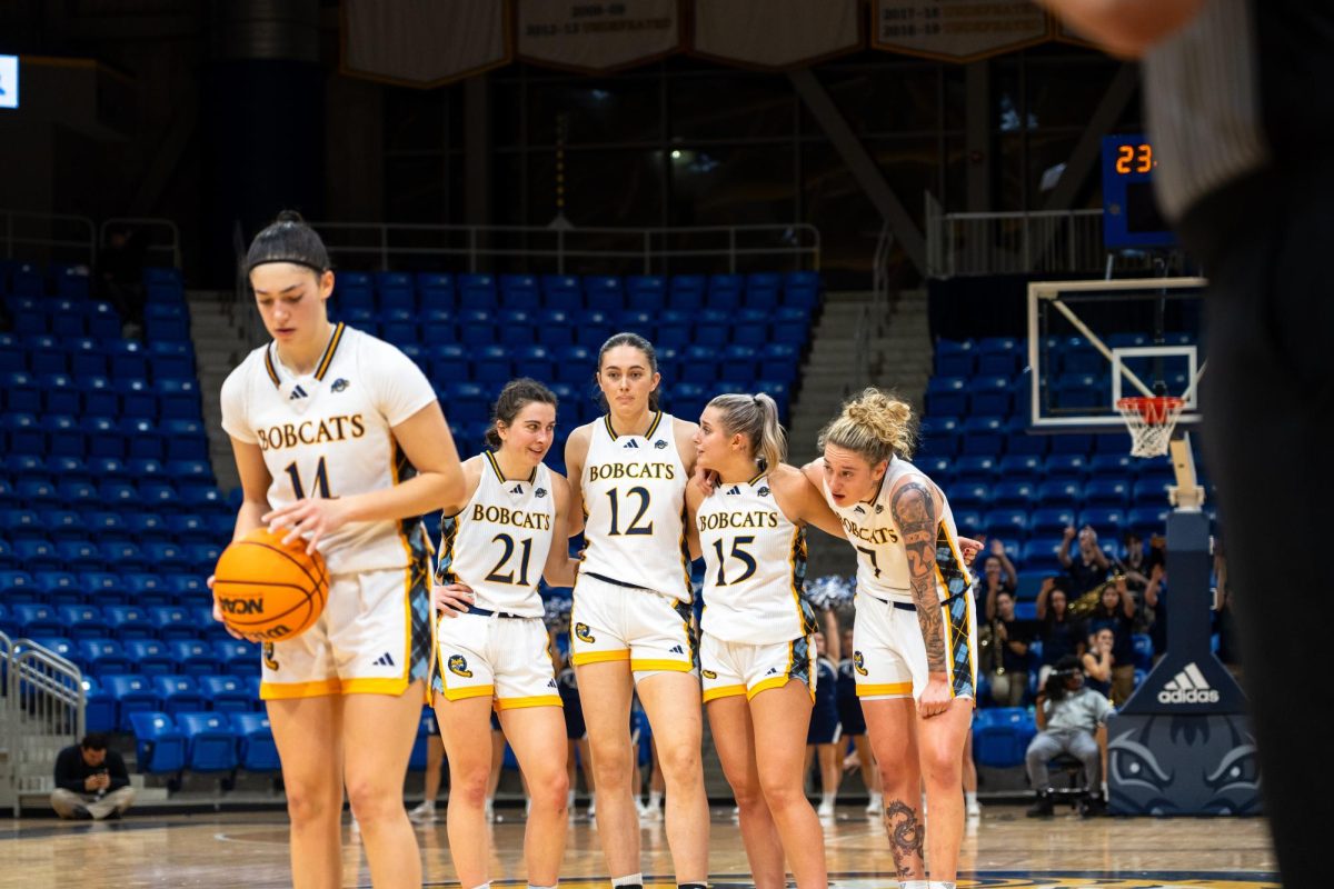 From left: senior guard Jackie Grisdale, junior forward Ella O'Donnell, sophomore guard Karson Martin and graduate student forward Caranda Perea huddles while freshman guard Gal Raviv shoots a free throw on Nov. 21 against Cornell. 