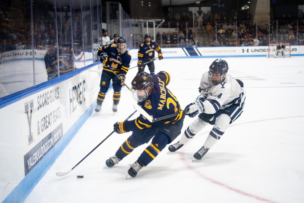 Junior forward Mason Marcellus skates with the puck up the boards against Yale on Nov. 7.
